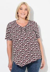 T-shirt à manches courtes dans un motif de cœurs noir, blanc et rouge foncé, avec un col rond et une coupe fluide et décontractée.