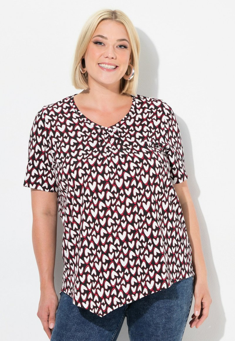 T-shirt à manches courtes dans un motif de cœurs noir, blanc et rouge foncé, avec un col rond et une coupe fluide et décontractée.