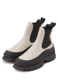 Chunky ankle boots in beige and black leather, featuring stretchy side panels, a thick rubber sole, and pull tabs for easy wear.