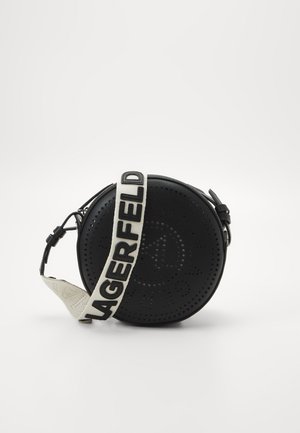 Sac bandoulière rond en cuir noir avec logo perforé et sangle blanche réglable portant le texte noir "KARL LAGERFELD".