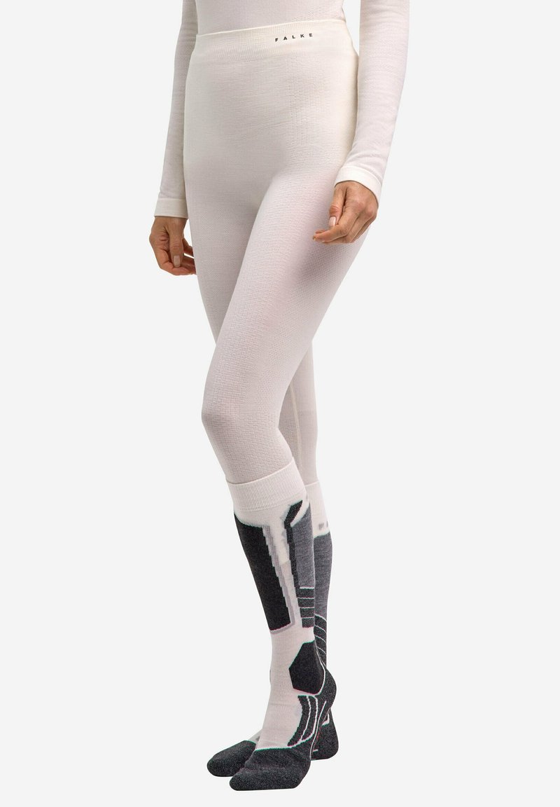 Leggings thermiques blancs avec une finition texturée et une taille haute. Mariés avec des chaussettes hautes noires et grises à motifs.