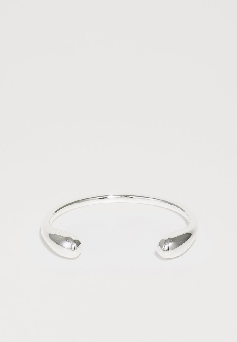 Hõbedane mansetibraats, millel on sile ja minimalistlik disain ning kitsenevad otsad. Pinnal on poleeritud viimistlus ja ühtlane kuju.