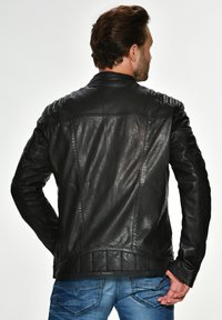 Schwarze Lederjacke mit gesteppten Schulterdetails und glatter Textur, ausgestattet mit einem Stehkragen und tailliertem Schnitt.