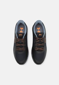 Czarne buty sportowe z siateczkowymi panelami, pomarańczowymi sznurówkami i logo. Szara wyściółka i wkładka. Teksturowana gumowa podeszwa zapewniająca przyczepność.