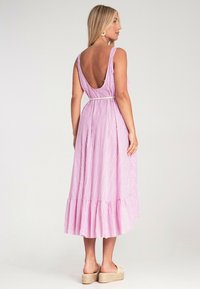 Langes, pink gestreiftes Kleid mit tiefem Rückenausschnitt, tailliertem Bund und rüschensaum. Hergestellt aus leichtem Stoff, mit breiten Schulterträgern und lockerer Passform.