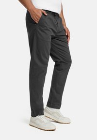 Sivé bavlnené nohavice s rovnou nohavicou, s bočnými vreckami a plochým predným dielom, doplnené bielymi teniskami.