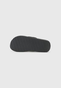 Black rubber shoe sole with a textured, ridged surface. Round shape at the toe with a smooth edge and no visible design patterns.