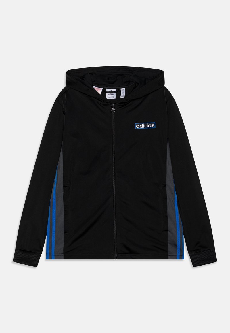 Veste de sport noire avec zip, capuche, rayures latérales bleues et grises, et logo brodé sur la poitrine. Texture lisse et design ajusté.