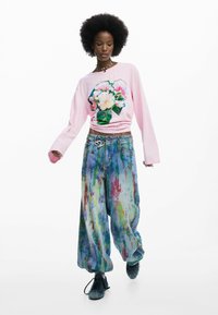 Roosa pika varrukaga pusa lillelise graafikaga. Värvikad abstraktsed lahtised teksapüksid. Komplekti lõpetavad mustad kingad.