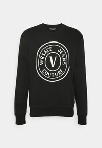Svart sweatshirt i bomullsblandning med en stor vit cirkulär logotyp med texten "VERSACE JEANS COUTURE" och en central "V"-design.