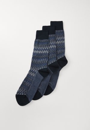 Tre par marinblå strumpor med ett zigzag-mönster i olika nyanser. Mjukt bomullsmaterial med förstärkta mörka toppar och tår.