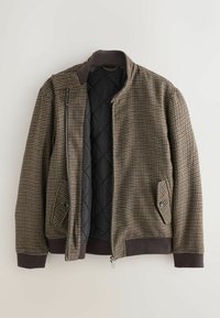 Rudas houndstooth raštas švarkas su užtrauktuku, raištinėmis rankovėmis ir juodos spalvos siuvinėta pamušalu, turi du priekiniai kišeniai.