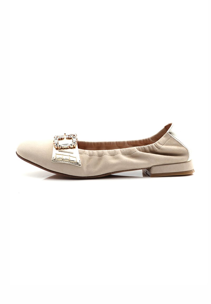 Zapato plano beige con punta redondeada, bordes elastizados y un acento decorativo de hebilla plateada. Textura suave con un tacón bajo.