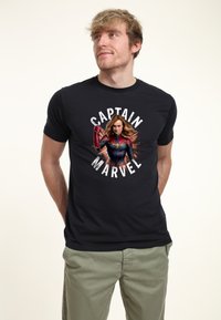 Czarna koszulka bawełniana z centralną grafiką superbohaterki w czerwono-niebieskim stroju, otoczona napisem "CAPTAIN MARVEL" na białym tle.
