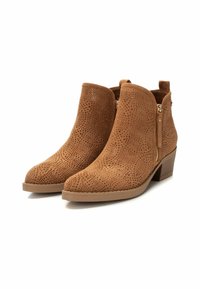 Botas de tobillo de ante en color marrón con textura perforada, cierre de cremallera lateral y tacón apilado. Punta redondeada y suela de goma flexible.