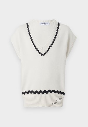 Kermanvärinen neuleetuparmu, jossa on V-pääntie, mustat aallotetut reunat ja ribatut yksityiskohdat helmassa, johon on brodeerattu logo.