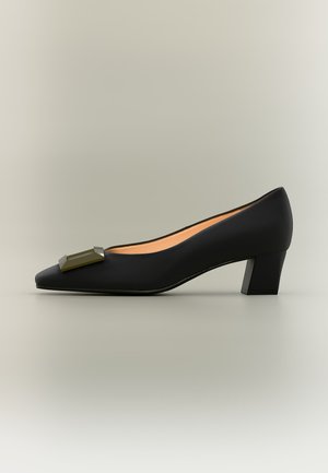 Zapato femenino negro de tacón bajo con punta puntiaguda y hebilla metálica rectangular en la parte delantera, mostrado de perfil sobre un fondo neutro.