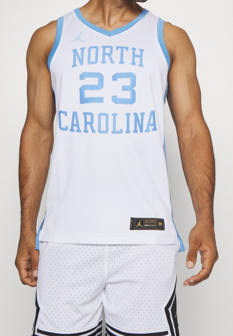 Maillot de basketball blanc avec des accents bleu clair, arborant « NORTH CAROLINA » et le numéro « 23 » en lettres audacieuses. Le matériau semble respirant avec une texture en mesh.