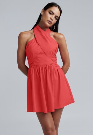 Koralfarvet kjole med halterneck og snoet detalje, tætsiddende liv og flagrende skørt. Glat stof og længde til midten af låret.