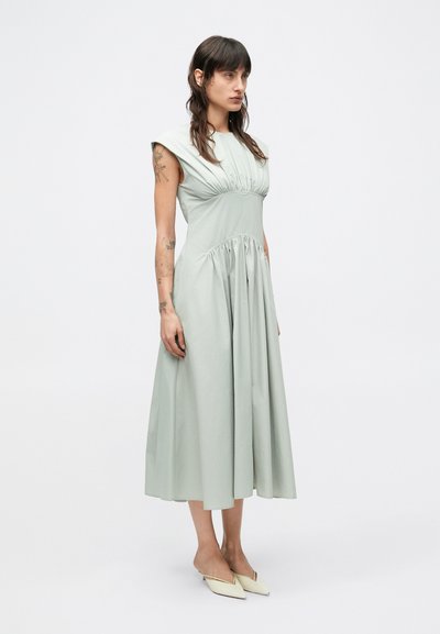 Svetlozelené midi šaty s priliehavým živôtikom, nariaseným pásom a krátkymi rukávmi. Vyrobené z hladkej látky, s plynulo prúdiacou sukňou.