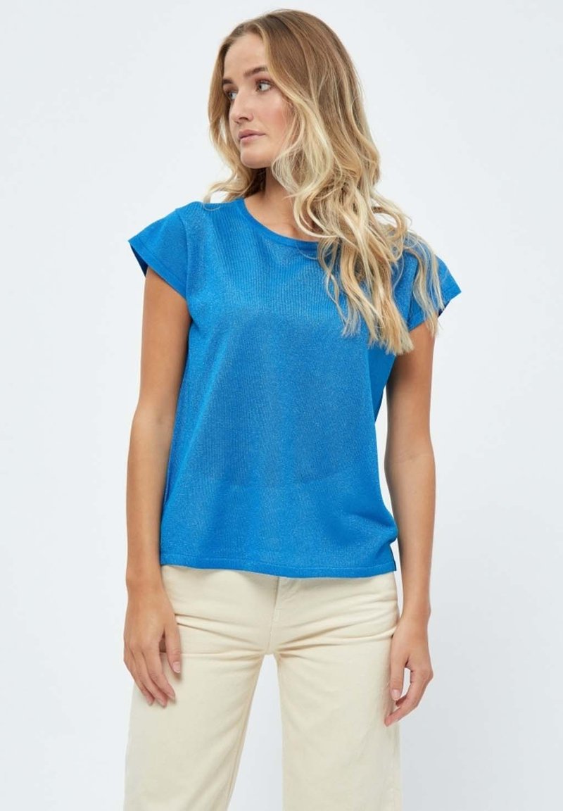 Top de manga corta azul brillante con un acabado texturizado y escote redondeado, combinado con pantalones beige claros. Tela suave y corte relajado.