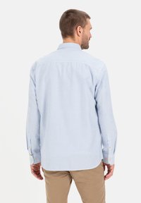 Hemelsblauwe en witte gestreepte shirt met lange mouwen, voorzien van een button-down kraag en manchetten, gemaakt van een zachte stof. Heeft een gebogen zoom.