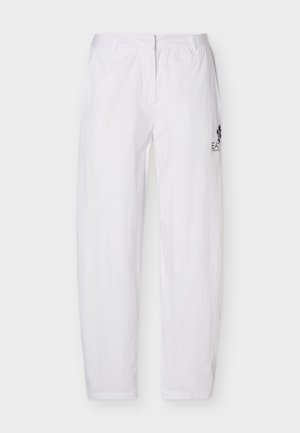Pantalon blanc taille élastique, coupe décontractée, avec logo noir sur la cuisse droite, présenté sur un fond clair uni.