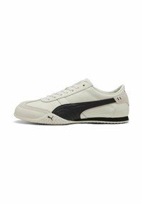 Zapatillas deportivas en blanco y negro con un empeine de cuero liso, puntera redondeada, suela de goma texturizada y un diseño de franjas laterales en contraste.