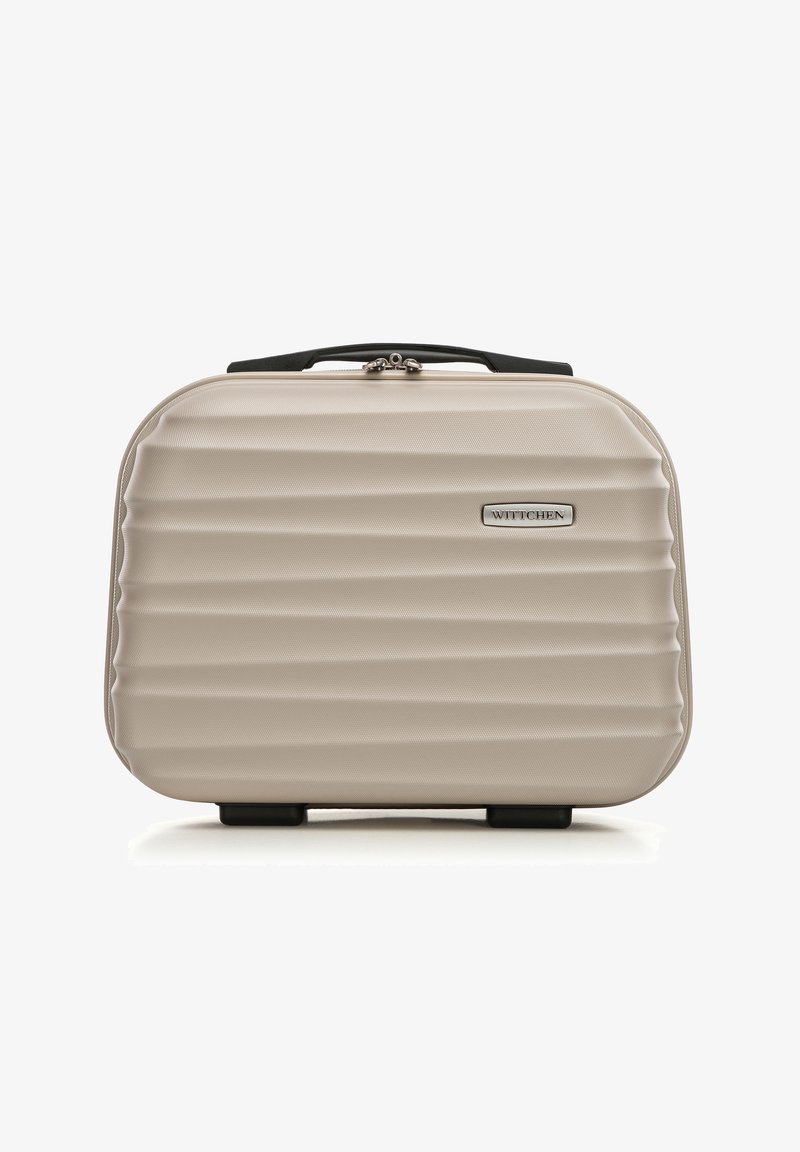 Valigia rigida beige con design a coste, hardware argentato, maniglia superiore e logo. La base presenta piedini protettivi per maggiore stabilità.