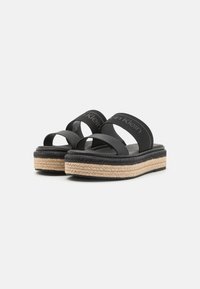 Sandali neri slip-on con due ampie cinghie, una suola intermedia in juta intessuta e una suola in gomma nera texturizzata. Logo Calvin Klein sulle cinghie.