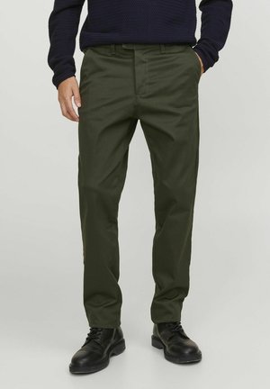 Dunkelgrüne, leichte Hose mit gerade geschnittenem Bein, vorderen Taschen und Gürtelschlaufen, kombiniert mit schwarzen Schnürstiefeln.