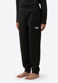 Čierne termo jogger nohavice s textúrovanou látkou, elastickým pásom a detailom loga na stehne. Navrhnuté pre teplo a pohodlie.