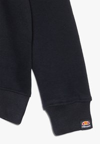 Svart sweatshirt med ribbad mudd och fåll. Har en texturerad tyg och en liten logopatch med färgade accenter på ärmen.