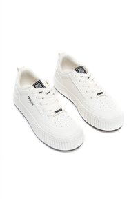 Białe sneakersy wykonane z materiału syntetycznego, z gładką teksturą, okrągłym noskiem, sznurowanym zapięciem i karbowaną podeszwą. Widoczna etykieta marki.