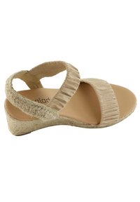 Sandale compensée beige avec une semelle en jute tressé, des brides en tissu texturé et une semelle intérieure douce et rembourrée. Design à bout ouvert avec des brides croisées sur le dessus.