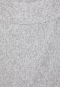 Světle šedá pletená látka s detaily žebrovaného límce, ukazující měkký, strukturovaný materiál a jemný melanžový vzor.