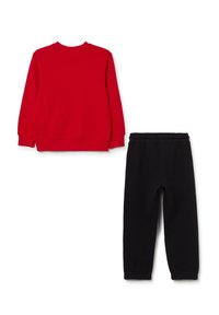 Roter Pullover mit Rundhalsausschnitt und gerippten Bündchen, kombiniert mit schwarzen Jogginghosen mit elastischem Bund. Beide aus weichem Stoff gefertigt.