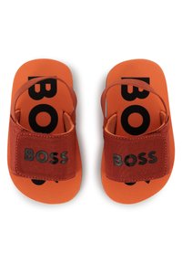 Piros és narancssárga csúszó szandálok, puha felső pánttal és texturált talpbetéttel, nagy fekete "BOSS" logóval.