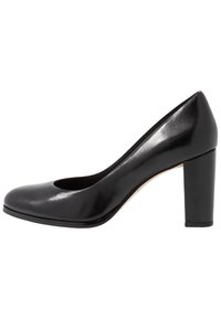 Chaussure à talon haut en cuir noir avec un bout arrondi et une découpe. Caractérisée par un talon carré épais et une surface lisse et brillante.