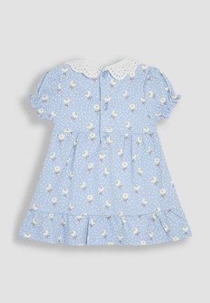 Lyseblå kjole med blomster mønster og hvide prikker. Har en hvid broderet krave, korte puffærmer og en rynket kant.