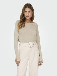 Helle beige, langärmlige Strickoberteil mit entspanntem Ausschnitt, kombiniert mit hoch taillierten weißen Hosen mit breitem Gürtel und Seitenschlitzen.