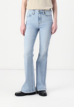 Lyseblå utsvingte jeans i denim med høy midje og klassisk fem-lommers design. Kombiner med svarte flate sko med frynsekant.