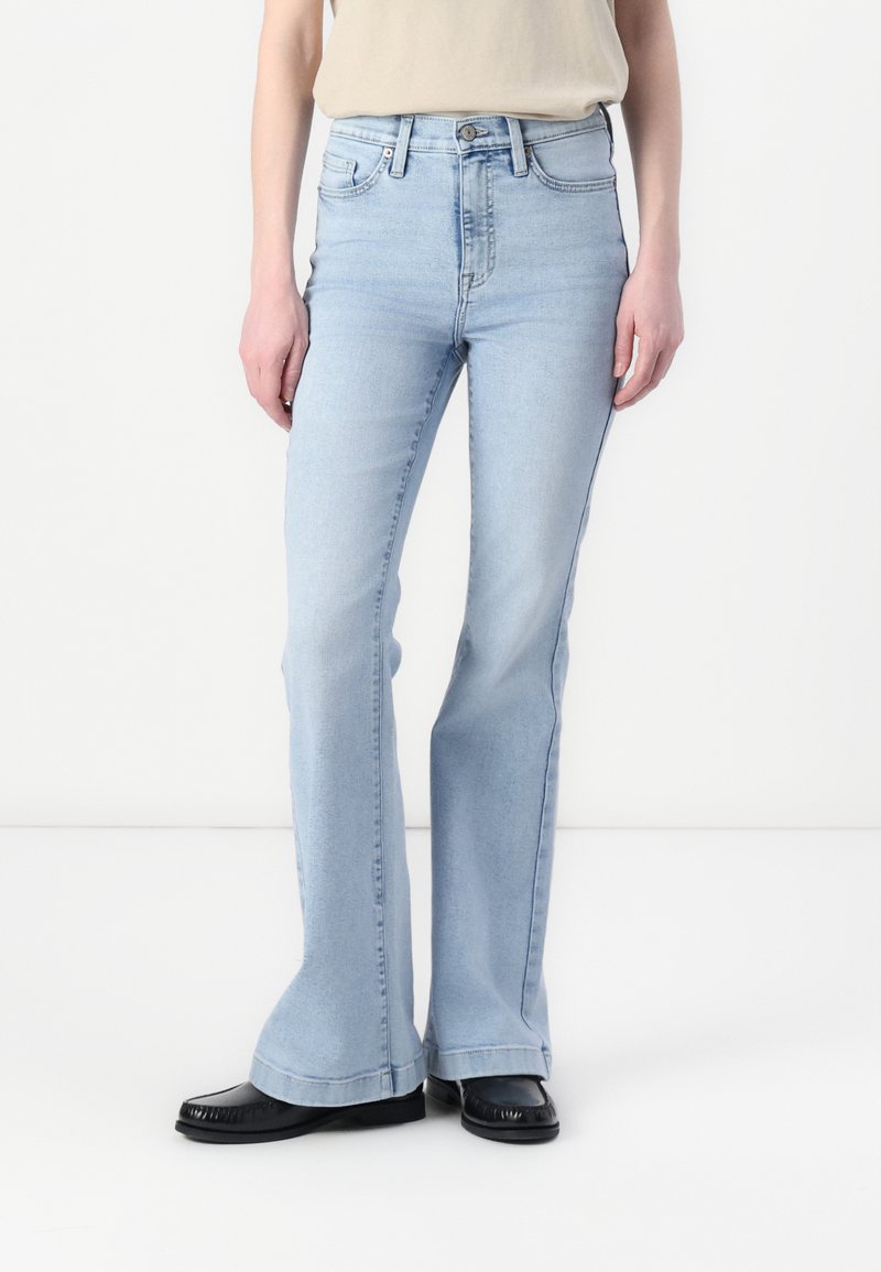 Lyseblå utsvingte jeans i denim med høy midje og klassisk fem-lommers design. Kombiner med svarte flate sko med frynsekant.