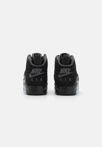 Sneaker Nike Air neri in morbida pelle scamosciata, con una forma del tallone distintiva e un logo prominente sul retro. Dettaglio della suola traslucida incluso.