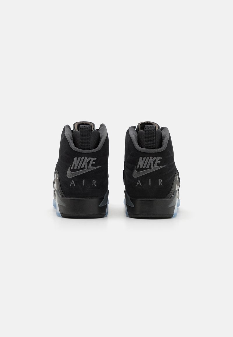 Baskets Nike Air noires en matériau suédé doux, avec une forme de talon distinctive et un logo bien en vue à l'arrière. Détail de semelle translucide inclus.