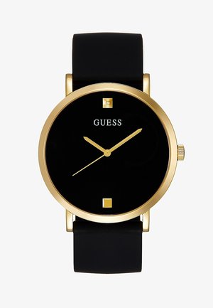 Cadran de montre noir avec bordure et aiguilles dorées, deux marqueurs horaires carrés, bracelet noir, et logo "GUESS" à la position 12 heures.
