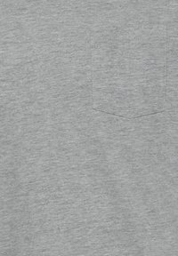 T-shirt in cotone grigio con finitura testurizzata e una piccola tasca a toppa sul lato sinistro del petto. Design semplice, senza motivi o grafiche.