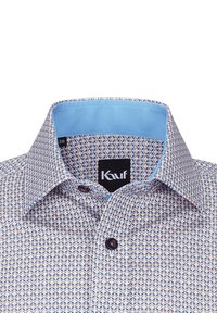 Camicia a motivi con un design geometrico in beige, blu e marrone. Interno del colletto azzurro e bottone scuro con l'etichetta del marchio visibile.