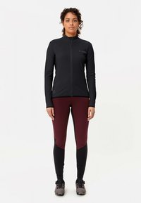 Svart zip-up jacka tillsammans med vinröda och svarta leggings, med åtsittande design och slät textur, lämpad för atletisk klädsel.