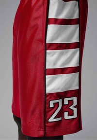 Short de basket rouge avec des bandes blanches horizontales et le numéro 23 sur le côté, avec un petit logo Jumpman près de l'ourlet.